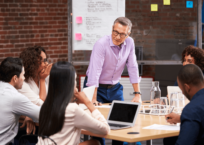 Business people round a table with a laptop on Building a business case for the implementation of new finance software blog page